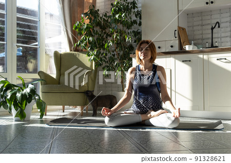 Middle aged woman practicing meditation at home, calm senior middle aged lady in lotus pose doing yoga for mental balance breathing air relaxing Middle aged woman practicing meditation at home, calm senior middle aged lady in lotus pose doing yoga for mental balance breathing air relaxing 91328621