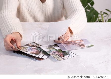 woman sitting at desk and looking at printed photos, remember nostalgia for a day of rest. photography cards, background. Mock up woman sitting at desk and looking at printed photos, remember nostalgia for a day of rest. photography cards, background. Mock up 91328638