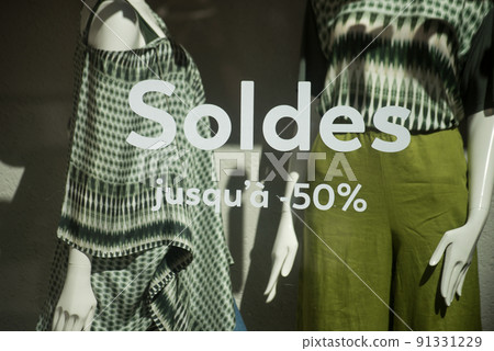 closeup of discount sign "SOLDES jusqu'a 50%" in french, the traduction of (sales until 50%) on window in french fashion store showroom on summer clothes background closeup of discount sign "SOLDES jusqu'a 50%" in french, the traduction of (sales until 50%) on window in french fashion store showroom on summer clothes background 91331229