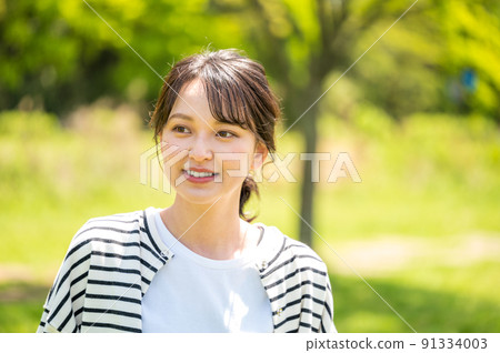 A young and cute woman enjoying nature outdoors on a sunny day 91334003