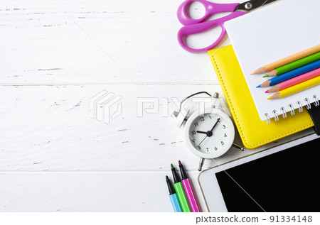 A tablet with an empty screen and office supplies on a white wooden background. Concept app for school children or online learning. Copy space A tablet with an empty screen and office supplies on a white wooden background. Concept app for school children or online learning. Copy space 91334148