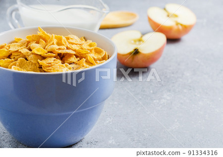 Corn flakes in a blue Cup and Apple slices. Useful Breakfast in the morning. Copy space 91334316