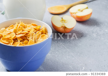 Corn flakes in a blue Cup and Apple slices. Useful Breakfast in the morning. Copy space Corn flakes in a blue Cup and Apple slices. Useful Breakfast in the morning. Copy space 91334369