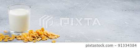 Corn flakes on a concrete background and milk in a glass. Side view. Copy space Corn flakes on a concrete background and milk in a glass. Side view. Copy space 91334384