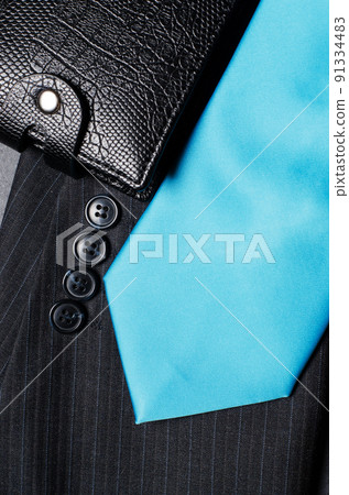 Blue men's necktie, jacket sleeve, and black wallet. Concept image of a successful business man 91334483