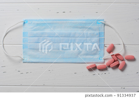 Medical disposable mask, tablets on a white background. The concept of protection during an epidemic of the disease. Copy space. Flat top view Medical disposable mask, tablets on a white background. The concept of protection during an epidemic of the disease. Copy space. Flat top view 91334937