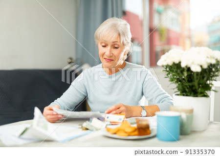 Elderly woman counting money at home 91335370