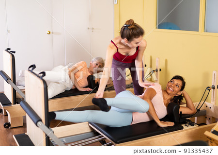 Female trainer helps a woman do stretching exercises Female trainer helps a woman do stretching exercises 91335437