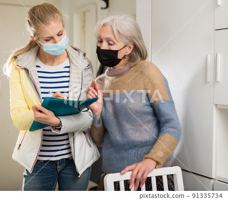 Mature woman in protective mask answers questions of interviewer at home 91335734