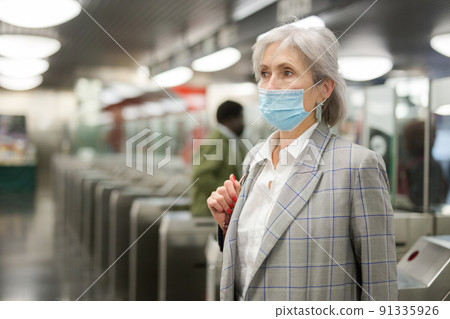 Senior woman in mask at entrance to subway station 91335926