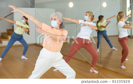 Female pensioner in mask exercising dance moves 91335929
