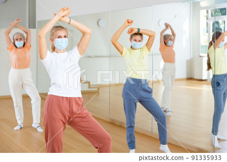 Woman in mask learning aerobic dance with her family in studio 91335933