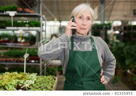 Focused woman garden shop owner having phone conversation Focused woman garden shop owner having phone conversation 91335955
