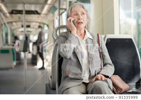 Woman talking on phone in tram Woman talking on phone in tram 91335999