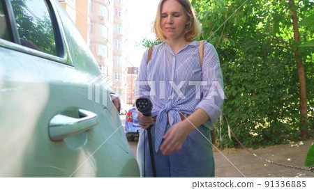 woman plugging in an electric car at outlet socket. woman plugging in an electric car at outlet socket. 91336885