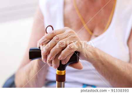 Hands of an old woman on cane closeup 91338393