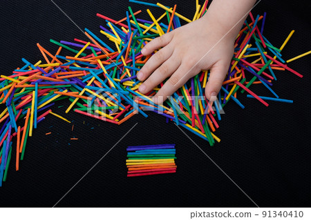 Kid playing with coloured wooden sticks for creativity Kid playing with coloured wooden sticks for creativity 91340410