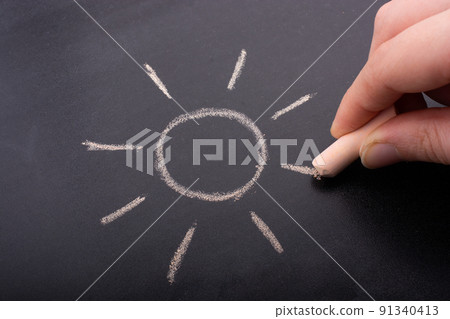 Child drawing sun with chalk shape on blackboard Child drawing sun with chalk shape on blackboard 91340413