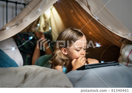 Happy cute little boy playing in a teepee tent at home. Happy cute little boy playing in a teepee tent at home. 91340481