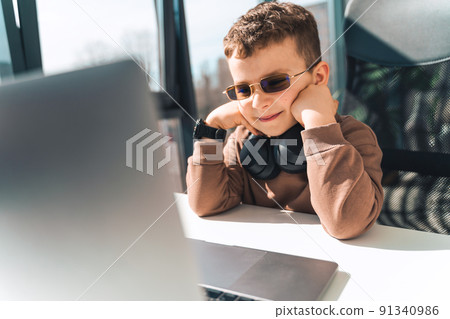 Schoolboy watches online video lessons on laptop. Studying during an epidemic Schoolboy watches online video lessons on laptop. Studying during an epidemic 91340986