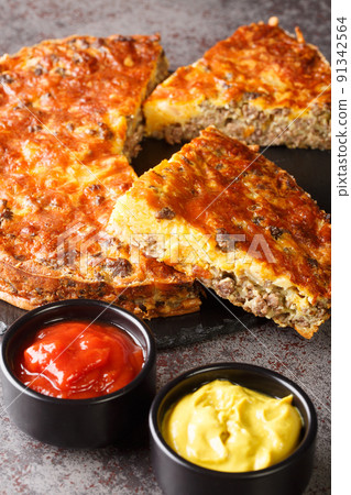 Cheeseburger Pie with ground beef cheddar cheese and onion close-up on a slate board. vertical Cheeseburger Pie with ground beef cheddar cheese and onion close-up on a slate board. vertical 91342564