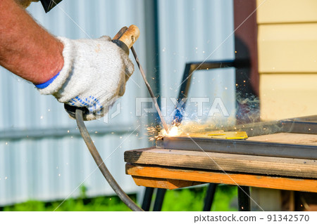 Electric arc welding electrode in the welder's hand. Electric arc welding electrode in the welder's hand. 91342570
