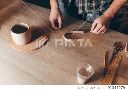 Potter creates the details for the ceramic cup. 91343079