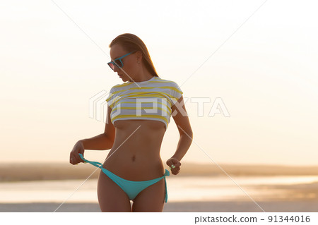 Sexy model in crop top and bikini panties on beach Sexy model in crop top and bikini panties on beach 91344016