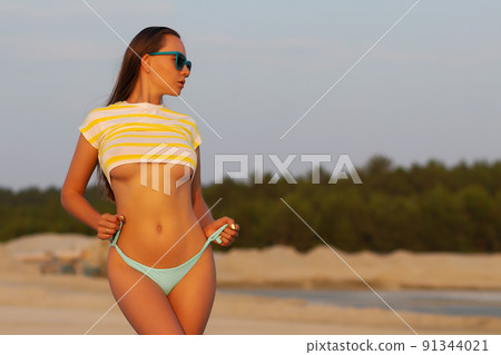 Sexy model in crop top and bikini panties on beach Sexy model in crop top and bikini panties on beach 91344021