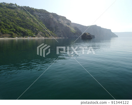 Aerial view from above on calm azure sea and volcanic rocky shores. Small waves on water surface in motion blur. Nature summer ocean sea beach background. Nobody. Holiday, vacation and travel concept Aerial view from above on calm azure sea and volcanic rocky shores. Small waves on water surface in motion blur. Nature summer ocean sea beach background. Nobody. Holiday, vacation and travel concept 91344122