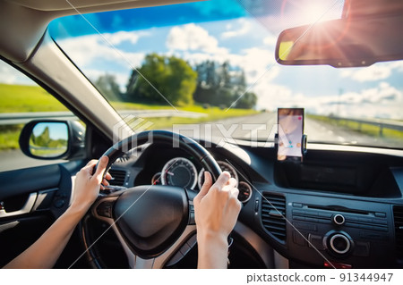 Woman driving a car and using a smrt phone as a navigator Woman driving a car and using a smrt phone as a navigator 91344947