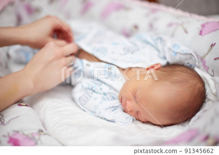 Mother dressing her cute hewborn baby daughter 91345662