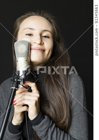 Young Chinese or Japanese cheerful woman hugs mic smiling in music studio alone 91345663