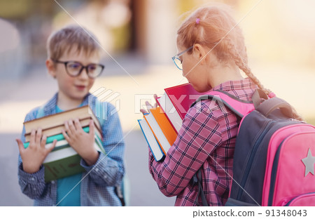 Girl and boy in glasses standing with books in their hands. 91348043