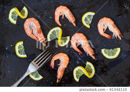 shrimp, lemon and sea salt with fork on a dark black background shrimp, lemon and sea salt with fork on a dark black background 91348110