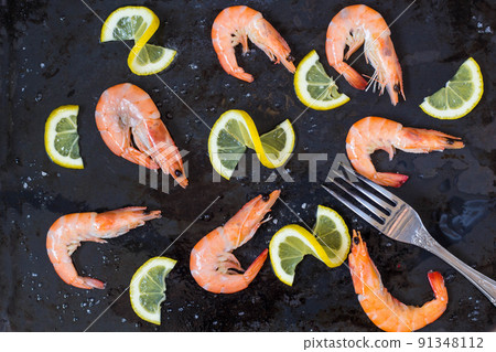 shrimp, lemon and sea salt with fork on a dark black background shrimp, lemon and sea salt with fork on a dark black background 91348112