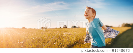 Happy child running through a summer field at evening sunset Happy child running through a summer field at evening sunset 91348673