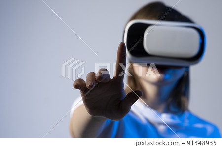Woman in VR headset trying to touch objects in virtual reality. 91348935