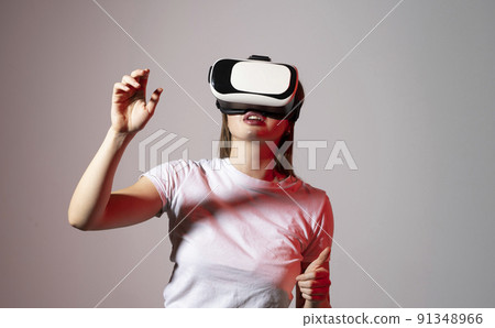 Young woman working in VR goggles on a grey background. Modern architect using virtual reality glasses at workplace. Designer working in augmented reality vr studio. Young woman working in VR goggles on a grey background. Modern architect using virtual reality glasses at workplace. Designer working in augmented reality vr studio. 91348966