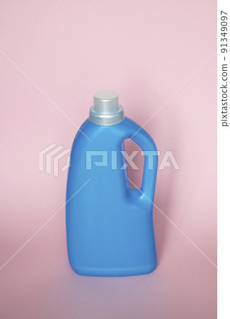Blue plastic bottle stands on pink background. Conditioner or liquid powder for washing. Capacity with space for copying. Layout for logo application. Blue plastic bottle stands on pink background. Conditioner or liquid powder for washing. Capacity with space for copying. Layout for logo application. 91349097