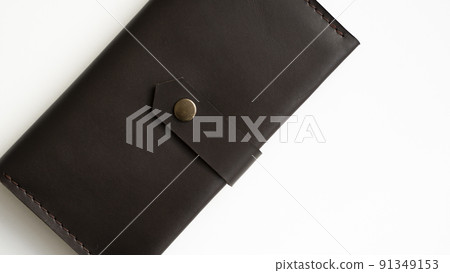 Top view of new dark brown genuine leather wallet with banknotes and credit card inside isolated on white background. 91349153