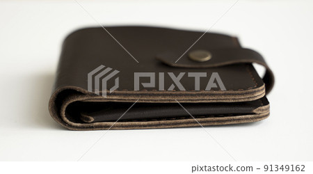 Side view of new dark brown genuine leather wallet with banknotes and credit card inside isolated on white background. 91349162