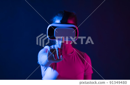 Metaverse technology concept. Woman with VR virtual reality goggles trying to touch something with a finger. Futuristic lifestyle. Metaverse technology concept. Woman with VR virtual reality goggles trying to touch something with a finger. Futuristic lifestyle. 91349480