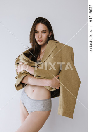 Portrait of young stylish woman posing in cotton underwear and trendy jacket isolated over grey studio background 91349632