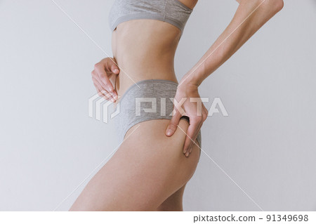 Cropped image of female fit buttocks in cotton underwear isolated over grey studio background. Anti-cellulite treatment 91349698