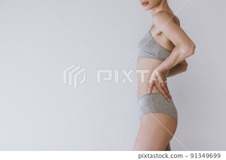 Side view image of slender female body in underwear isolated over grey studio background. Woman's heath care 91349699