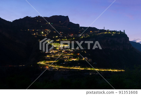 night view of a mountain village with glowing lanterns on a cliff 91351608