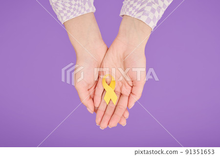 Female hands holding yellow ribbon on purple background for supporting people living and illness Female hands holding yellow ribbon on purple background for supporting people living and illness 91351653
