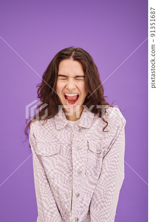 Portrait of young woman expressing her emotion by screaming isolated on purple background 91351687