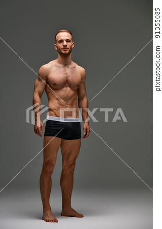 Young male athlete posing. Handsome athletic male power guy. Fitness muscular person. Young athlete showing muscles in the studio, posing shirtless on gray background. 91355085